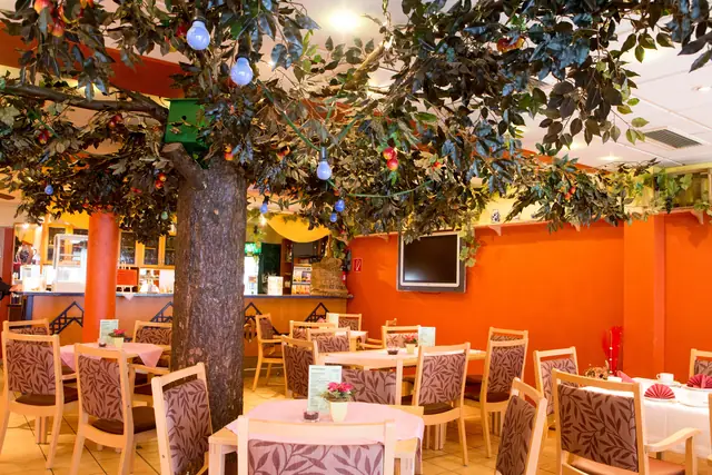 Cafeteria mit Baum, orangen Wänden und gedeckten Tischen